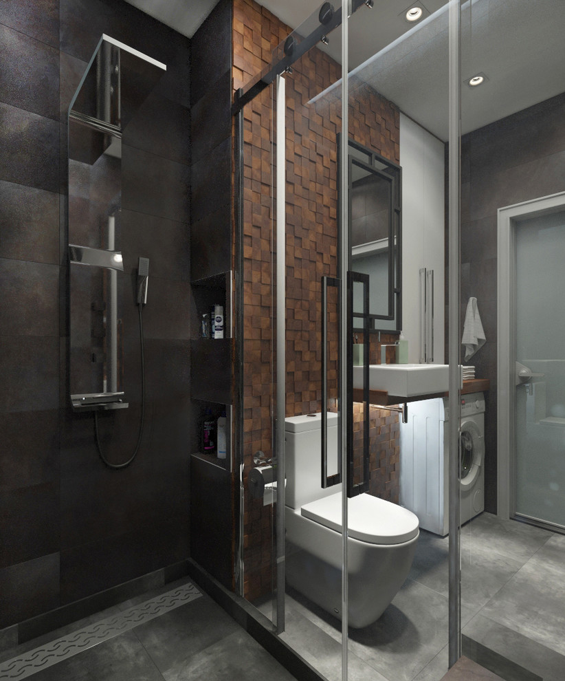 Exempel på ett mellanstort modernt brun brunt badrum med dusch, med släta luckor, våtrum, en toalettstol med hel cisternkåpa, brun kakel, keramikplattor, bruna väggar, klinkergolv i porslin, ett fristående handfat, träbänkskiva, grått golv och dusch med skjutdörr