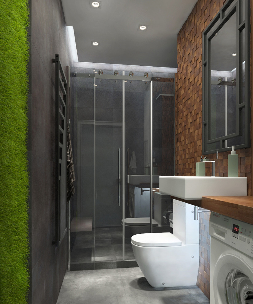 Inspiration för mellanstora moderna brunt badrum med dusch, med släta luckor, våtrum, en toalettstol med hel cisternkåpa, brun kakel, keramikplattor, bruna väggar, klinkergolv i porslin, ett fristående handfat, träbänkskiva, grått golv och dusch med skjutdörr