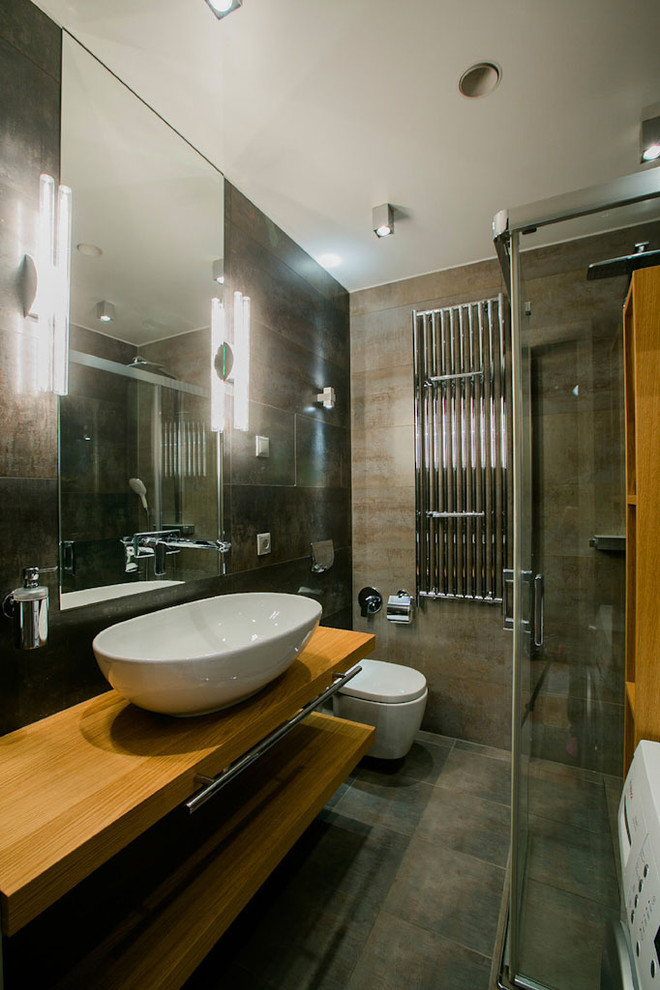 Exempel på ett stort industriellt badrum med dusch, med grå skåp, våtrum, en vägghängd toalettstol, grå kakel, grå väggar, betonggolv, ett piedestal handfat, träbänkskiva, grått golv och dusch med gångjärnsdörr