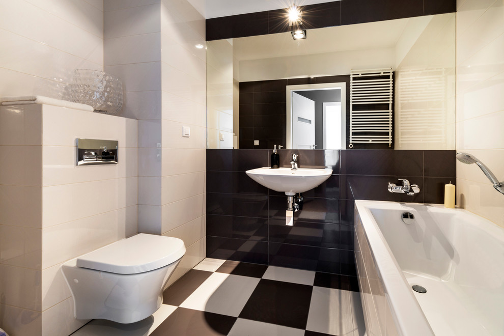 Пример оригинального дизайна: главная ванная комната среднего размера в современном стиле с ванной в нише, душем над ванной, инсталляцией, керамической плиткой, бежевыми стенами, полом из керамогранита, подвесной раковиной и черно-белой плиткой