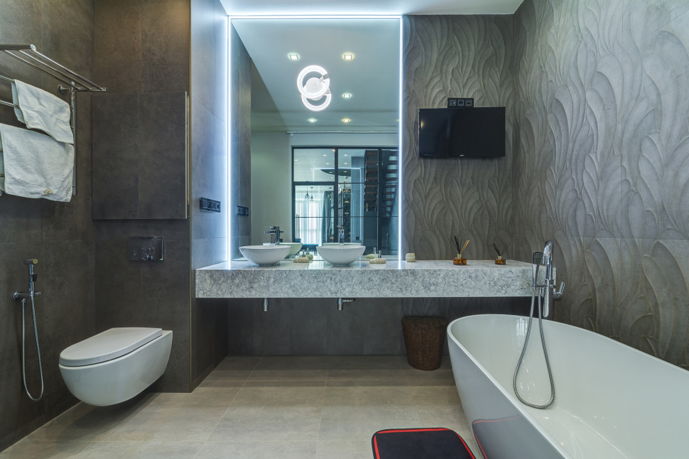 Источник вдохновения для домашнего уюта: ванная комната в современном стиле с отдельно стоящей ванной, инсталляцией, серой плиткой, настольной раковиной, серым полом и серой столешницей