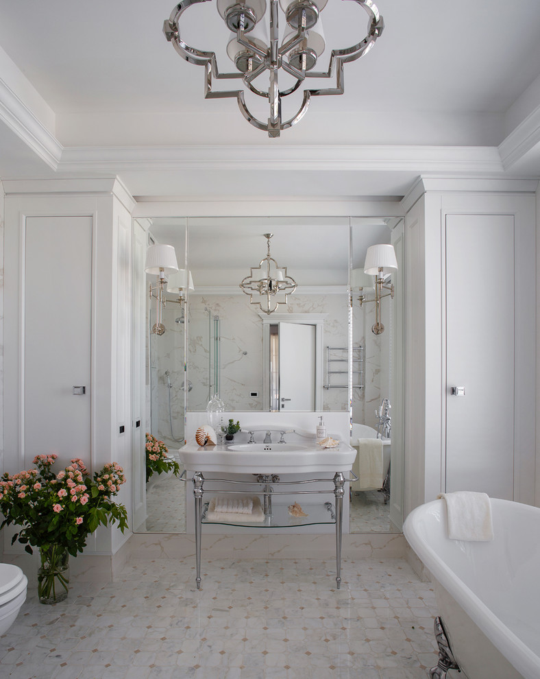 На фото: ванная комната в стиле неоклассика (современная классика) с ванной на ножках, белыми стенами, консольной раковиной и серым полом