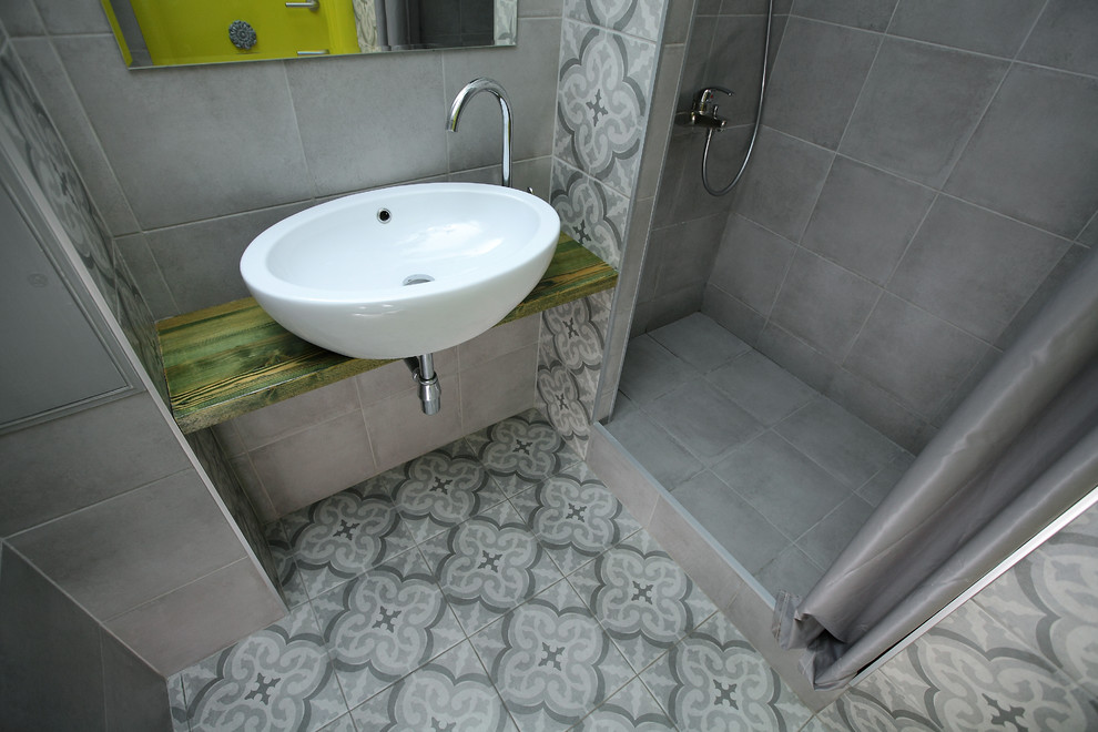 Idee per una piccola stanza da bagno con doccia etnica con doccia alcova, WC sospeso, piastrelle grigie, piastrelle in gres porcellanato, pareti grigie, pavimento in gres porcellanato, lavabo da incasso e pavimento grigio