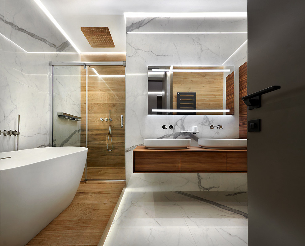 Photo of a large contemporary ensuite bathroom in Los Angeles with flat-panel cabinets, medium wood cabinets, a freestanding bath, an alcove shower, brown tiles, grey tiles, a vessel sink, wooden worktops, grey floors, a sliding door and brown worktops.
