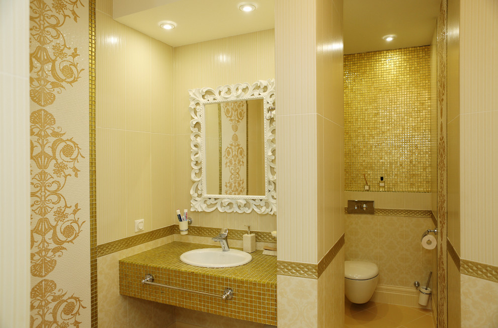 Exempel på ett klassiskt en-suite badrum, med en vägghängd toalettstol, gul kakel, gula väggar, klinkergolv i keramik, kaklad bänkskiva, mosaik och ett nedsänkt handfat
