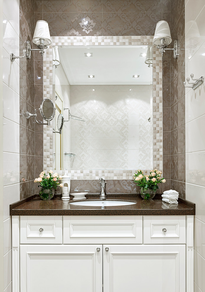 Klassisk inredning av ett litet en-suite badrum, med vita skåp, beige kakel, vit kakel, keramikplattor, ett undermonterad handfat, bänkskiva i akrylsten och luckor med infälld panel