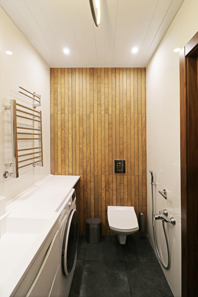 Стильный дизайн: ванная комната среднего размера в современном стиле с плоскими фасадами, белыми фасадами, душем в нише, инсталляцией, коричневой плиткой, плиткой под дерево, белыми стенами, полом из керамогранита, душевой кабиной, монолитной раковиной, столешницей из искусственного камня, черным полом, душем с раздвижными дверями, белой столешницей, тумбой под одну раковину, напольной тумбой и гигиеническим душем - последний тренд