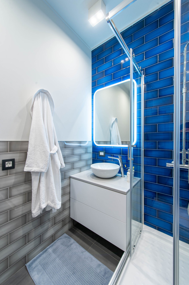 Стильный дизайн: маленькая ванная комната в скандинавском стиле с плоскими фасадами, серыми фасадами, угловым душем, инсталляцией, разноцветной плиткой, керамической плиткой, серыми стенами, полом из керамогранита, душевой кабиной, накладной раковиной, столешницей из искусственного камня, серым полом, душем с раздвижными дверями, серой столешницей, нишей, тумбой под одну раковину и подвесной тумбой для на участке и в саду - последний тренд