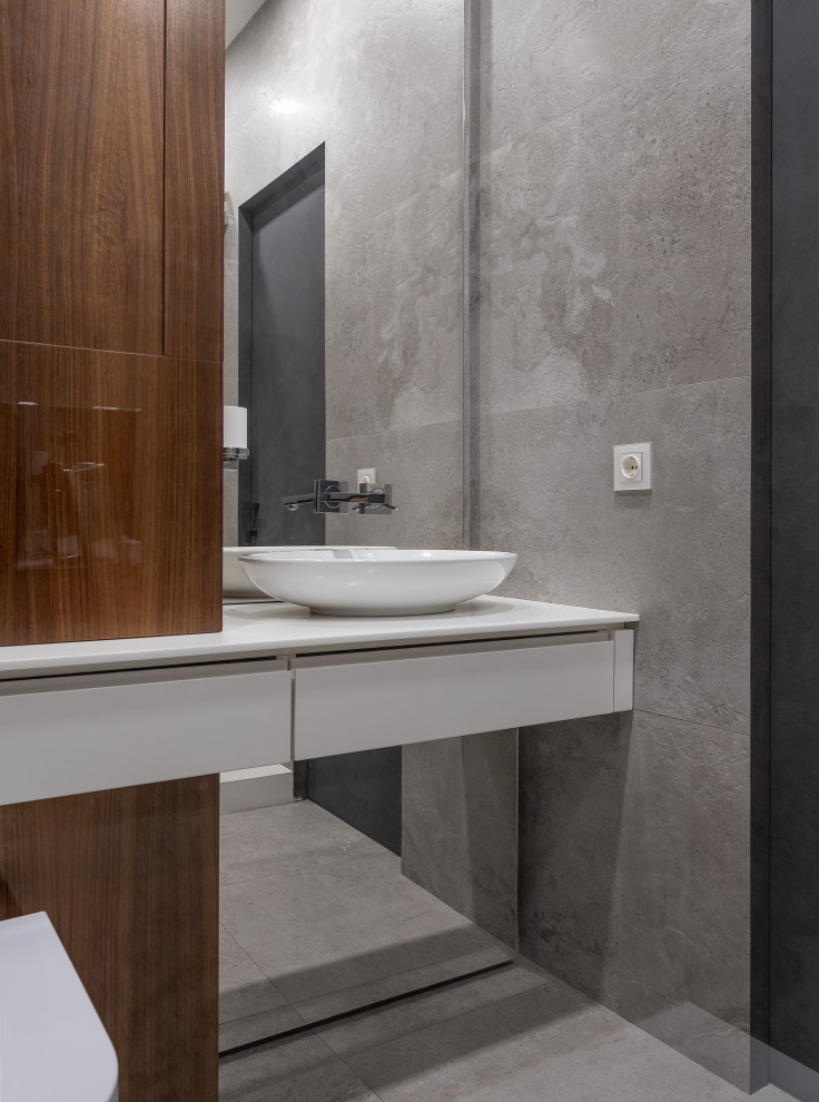 Modelo de cuarto de baño contemporáneo con armarios con paneles lisos, puertas de armario blancas, baldosas y/o azulejos grises, lavabo sobreencimera, suelo gris y encimeras blancas