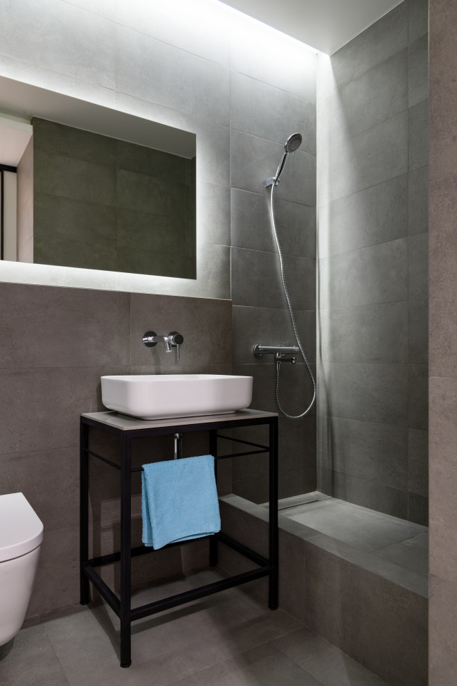 Foto på ett mellanstort funkis grå badrum med dusch, med svarta skåp, en dusch i en alkov, en vägghängd toalettstol, grå kakel, porslinskakel, klinkergolv i porslin, ett fristående handfat, grått golv och med dusch som är öppen