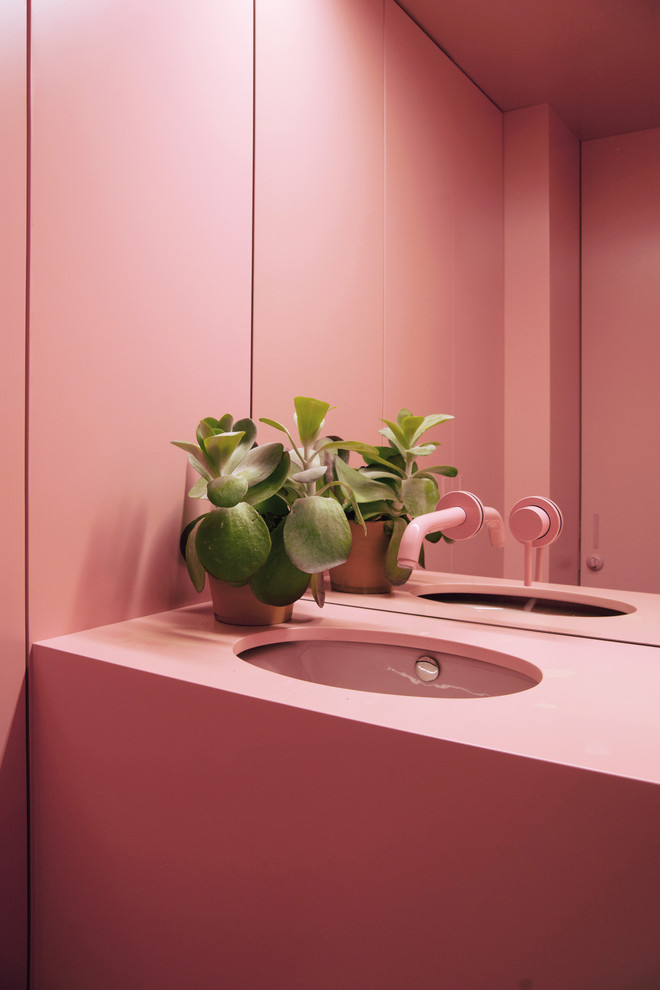 Aménagement d'une salle de bain contemporaine avec un mur rose, un lavabo encastré et un plan de toilette rose.