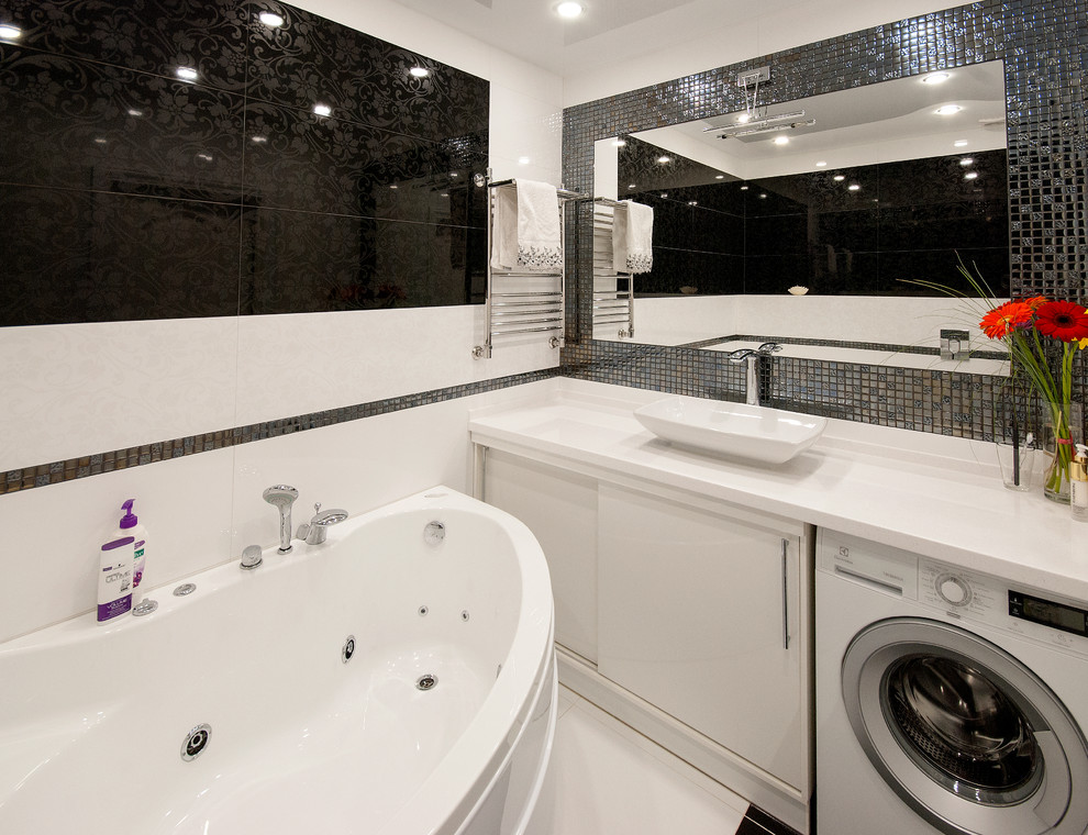 Пример оригинального дизайна: главная ванная комната среднего размера в современном стиле с плоскими фасадами, белыми фасадами, белой плиткой, керамической плиткой, полом из керамической плитки, настольной раковиной, столешницей из искусственного камня и гидромассажной ванной