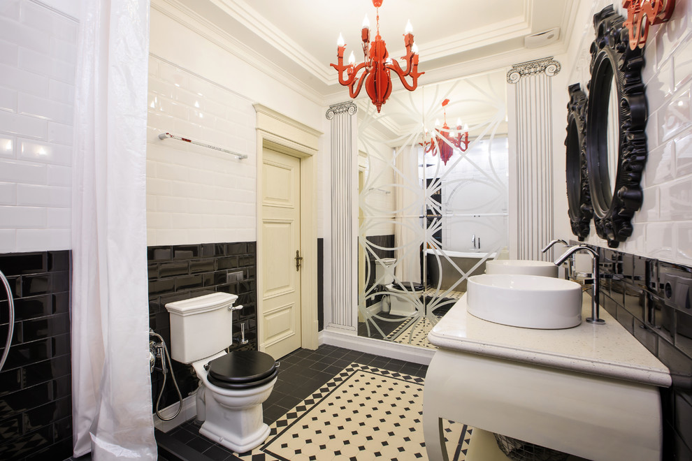 Klassisk inredning av ett badrum, med en toalettstol med separat cisternkåpa, vit kakel, svart och vit kakel, svart kakel, tunnelbanekakel och ett fristående handfat