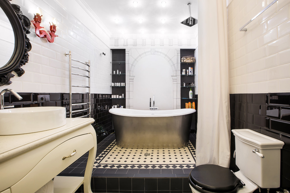Inredning av ett klassiskt badrum, med ett fristående badkar, en toalettstol med separat cisternkåpa, vit kakel, svart och vit kakel, svart kakel, tunnelbanekakel, ett fristående handfat, en öppen dusch, dusch med duschdraperi och släta luckor