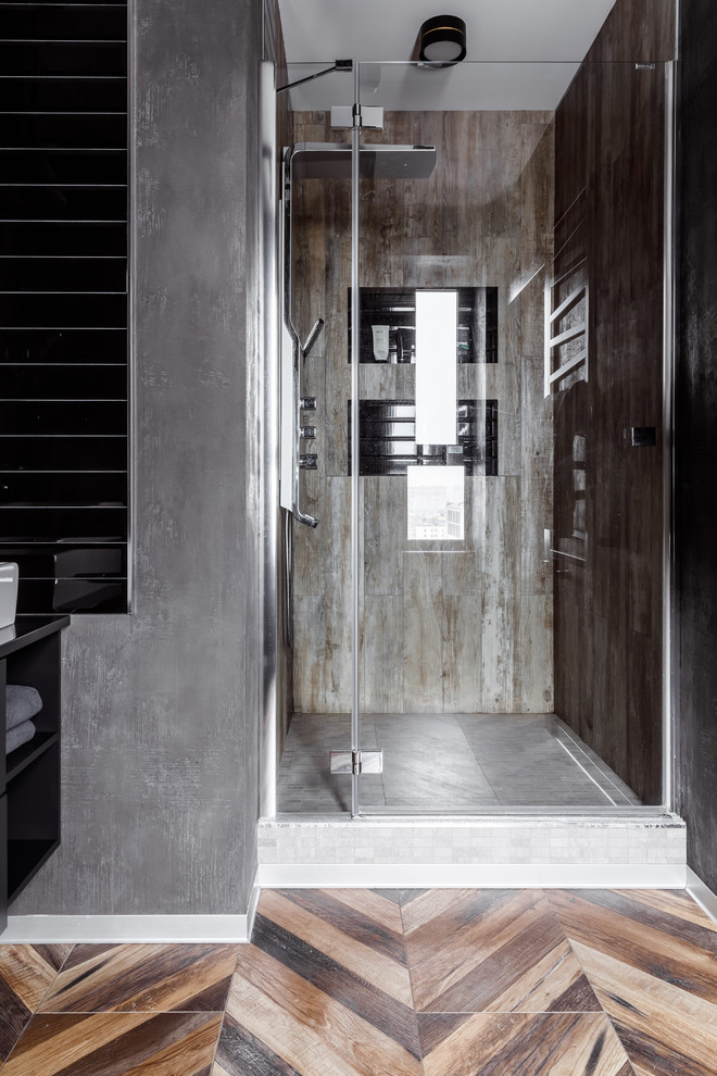 Esempio di una stanza da bagno con doccia industriale di medie dimensioni con doccia alcova, piastrelle nere, piastrelle in ceramica, pareti grigie, pavimento in gres porcellanato, pavimento marrone e porta doccia a battente