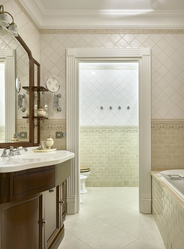 Пример оригинального дизайна: главная ванная комната в классическом стиле с фасадами с утопленной филенкой, бежевой плиткой, белой плиткой, керамической плиткой, бежевыми стенами, полом из керамической плитки, темными деревянными фасадами, душем над ванной, раздельным унитазом и накладной ванной