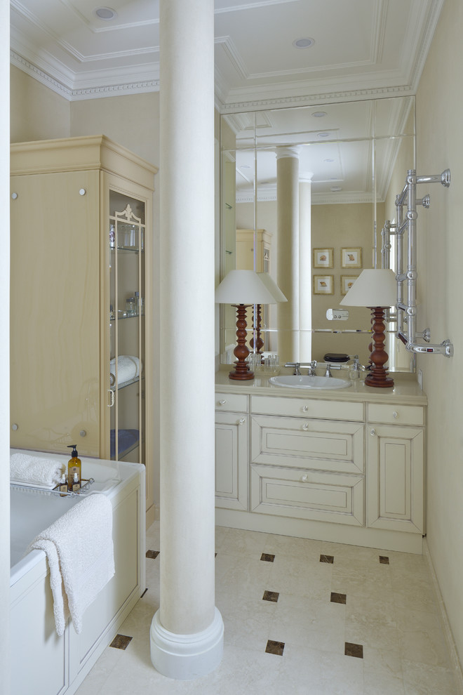 Esempio di una stanza da bagno padronale design con ante con bugna sagomata, ante in legno chiaro, vasca sottopiano, pareti beige, pavimento in marmo, lavabo da incasso e top in quarzo composito