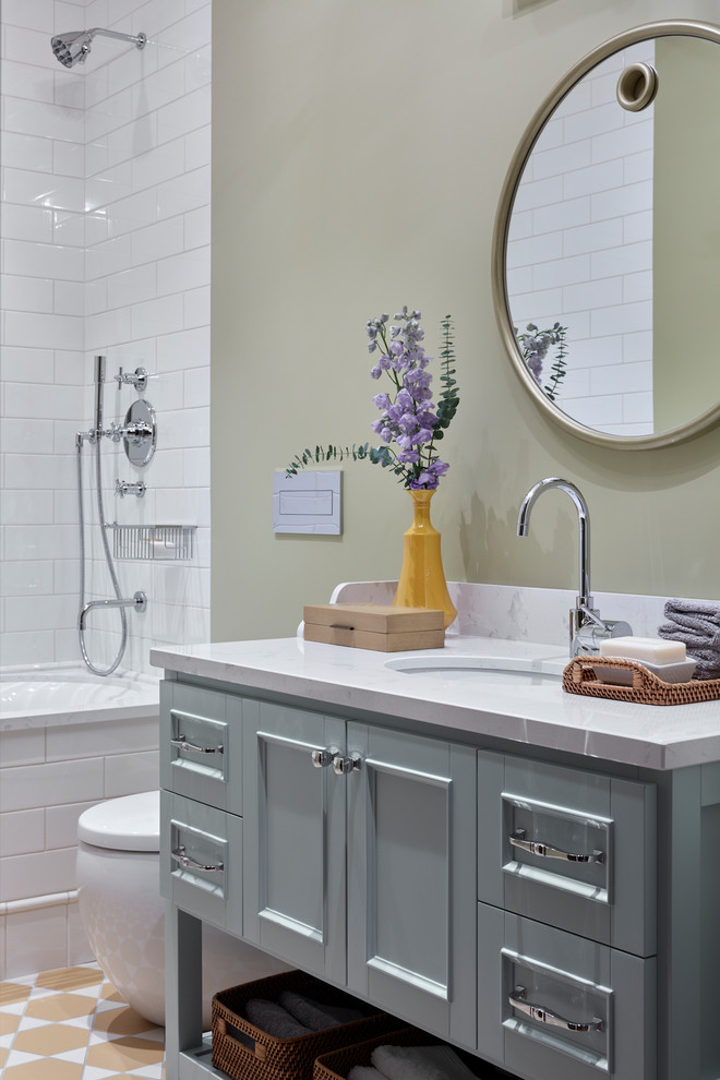 Inredning av ett klassiskt mellanstort badrum, med turkosa skåp, en dusch/badkar-kombination, en toalettstol med separat cisternkåpa, vit kakel, keramikplattor, cementgolv, bänkskiva i kvarts, gult golv, dusch med duschdraperi, luckor med infälld panel, ett badkar i en alkov, beige väggar och ett undermonterad handfat