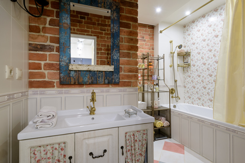 На фото: главная ванная комната в стиле шебби-шик с светлыми деревянными фасадами, шторкой для ванной, душем над ванной и монолитной раковиной с