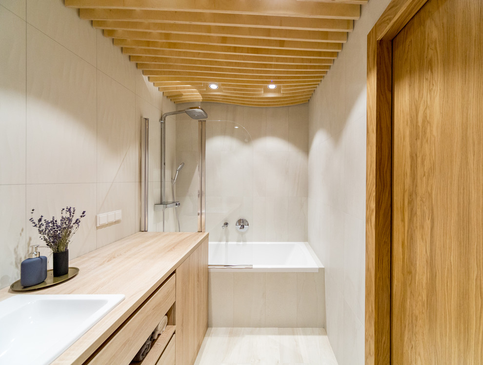 Идея дизайна: главная ванная комната среднего размера в современном стиле с плоскими фасадами, душем над ванной, бежевой плиткой, керамической плиткой, полом из керамогранита, накладной раковиной, столешницей из дерева, бежевым полом, светлыми деревянными фасадами, ванной в нише, бежевой столешницей и открытым душем