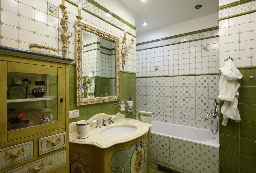 На фото: ванная комната в викторианском стиле с ванной в нише, белой плиткой, зеленой плиткой и врезной раковиной