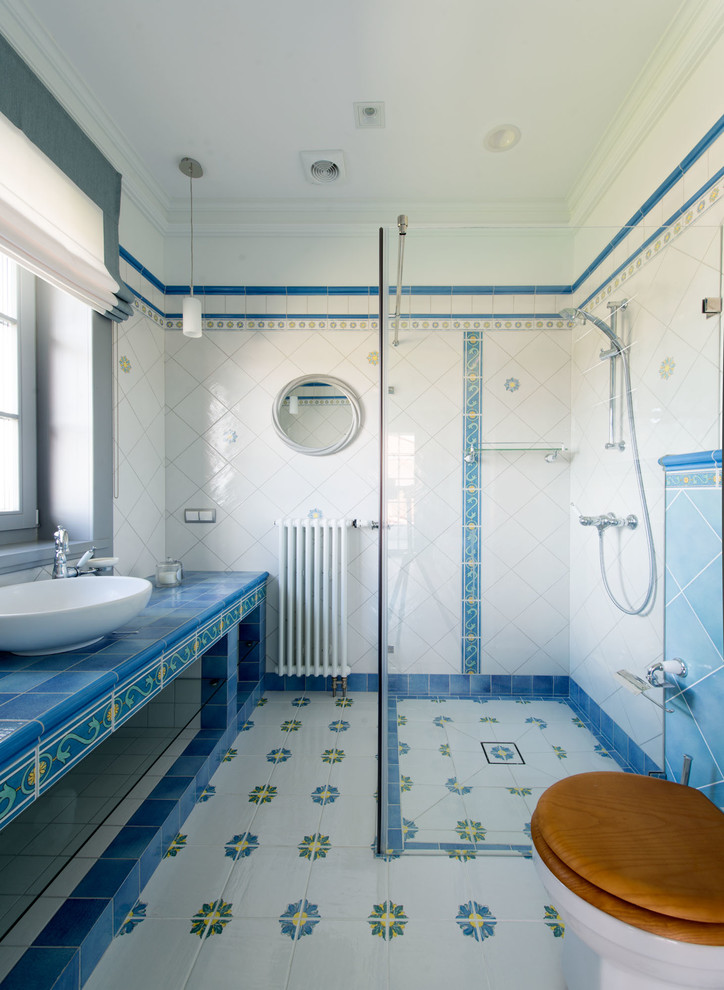 Großes Mediterranes Duschbad mit weißen Schränken, offener Dusche, farbigen Fliesen, Keramikfliesen, weißer Wandfarbe, Porzellan-Bodenfliesen, buntem Boden, Schiebetür-Duschabtrennung, Aufsatzwaschbecken, gefliestem Waschtisch und blauer Waschtischplatte