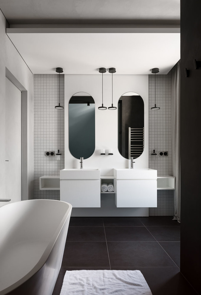 Esempio di una stanza da bagno contemporanea con ante lisce, ante bianche, vasca freestanding, piastrelle bianche, piastrelle a mosaico, lavabo a consolle e pavimento nero