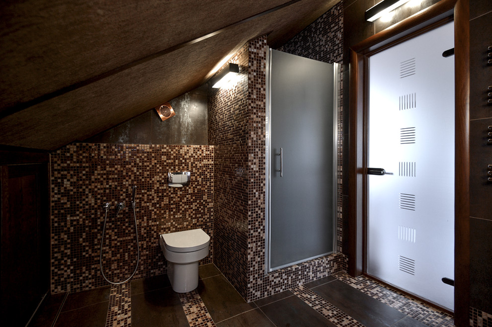 Eklektisk inredning av ett mellanstort badrum med dusch, med luckor med infälld panel, bruna skåp, en dusch i en alkov, en vägghängd toalettstol, brun kakel, mosaik, bruna väggar, klinkergolv i porslin, ett väggmonterat handfat, brunt golv och dusch med gångjärnsdörr