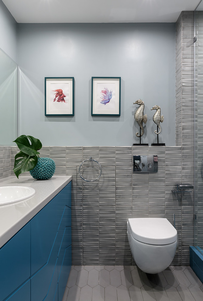 Inspiration för ett mellanstort funkis grå grått badrum med dusch, med turkosa skåp, en vägghängd toalettstol, grå kakel, keramikplattor, klinkergolv i keramik, ett nedsänkt handfat, bänkskiva i akrylsten, grått golv, släta luckor och grå väggar