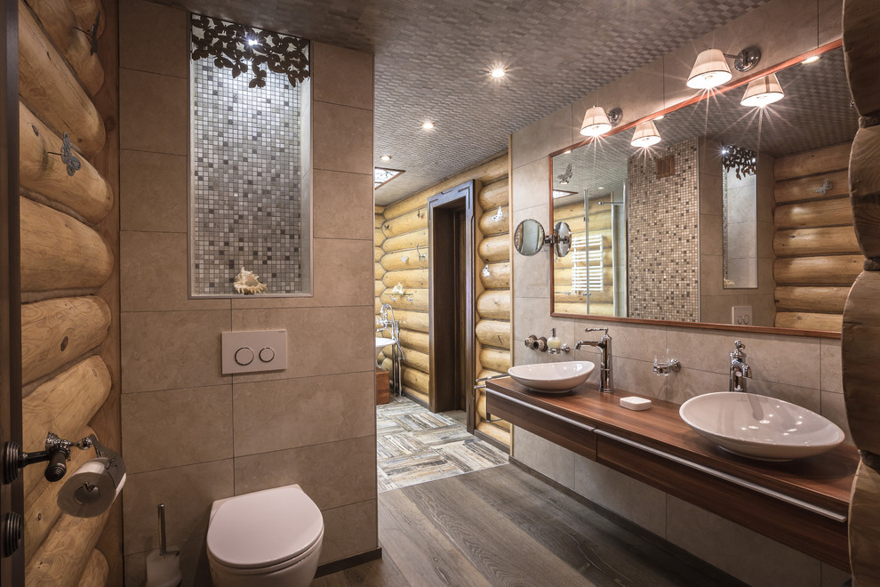 Cette photo montre une salle de bain nature avec WC suspendus, un carrelage multicolore, des carreaux de céramique, un sol en carrelage de céramique, un plan de toilette en bois et une vasque.