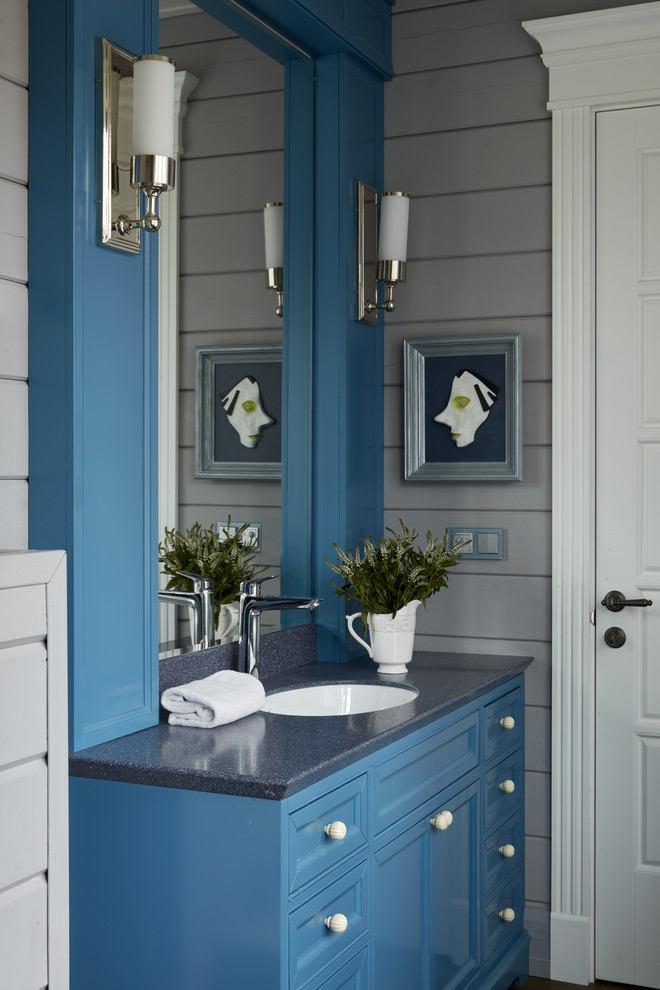 Modelo de cuarto de baño de estilo de casa de campo con armarios con paneles empotrados, puertas de armario azules, paredes grises, lavabo bajoencimera y encimeras grises