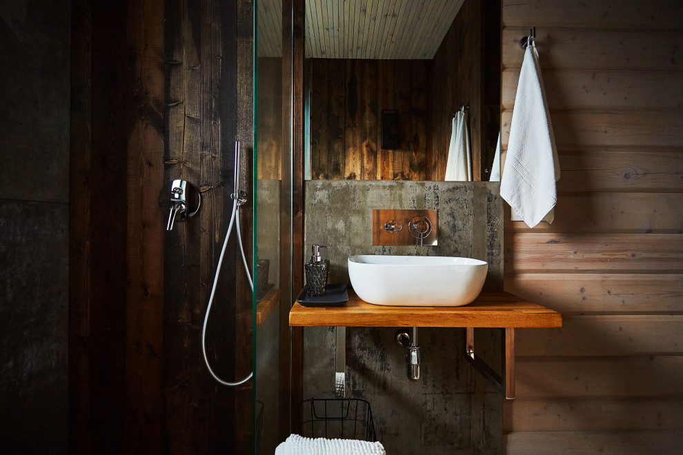 На фото: ванная комната среднего размера в стиле рустика с угловым душем, коричневыми стенами, душевой кабиной, подвесной раковиной, столешницей из дерева, коричневой столешницей, тумбой под одну раковину, подвесной тумбой и деревянными стенами