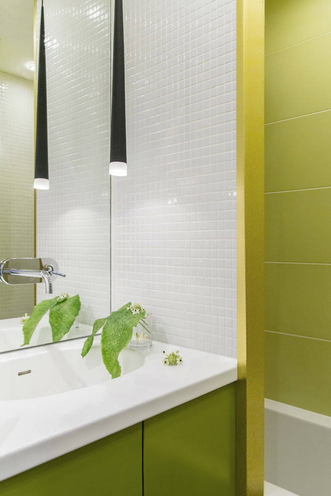 Modelo de cuarto de baño contemporáneo pequeño con armarios con paneles lisos, puertas de armario verdes, bañera empotrada, sanitario de pared, baldosas y/o azulejos blancos, baldosas y/o azulejos en mosaico, paredes verdes, suelo de mármol, lavabo integrado y encimera de acrílico