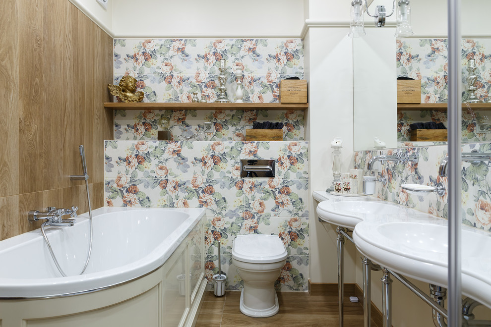 Foto de cuarto de baño principal tradicional con bañera esquinera, baldosas y/o azulejos multicolor, suelo marrón, sanitario de una pieza, paredes multicolor y lavabo tipo consola