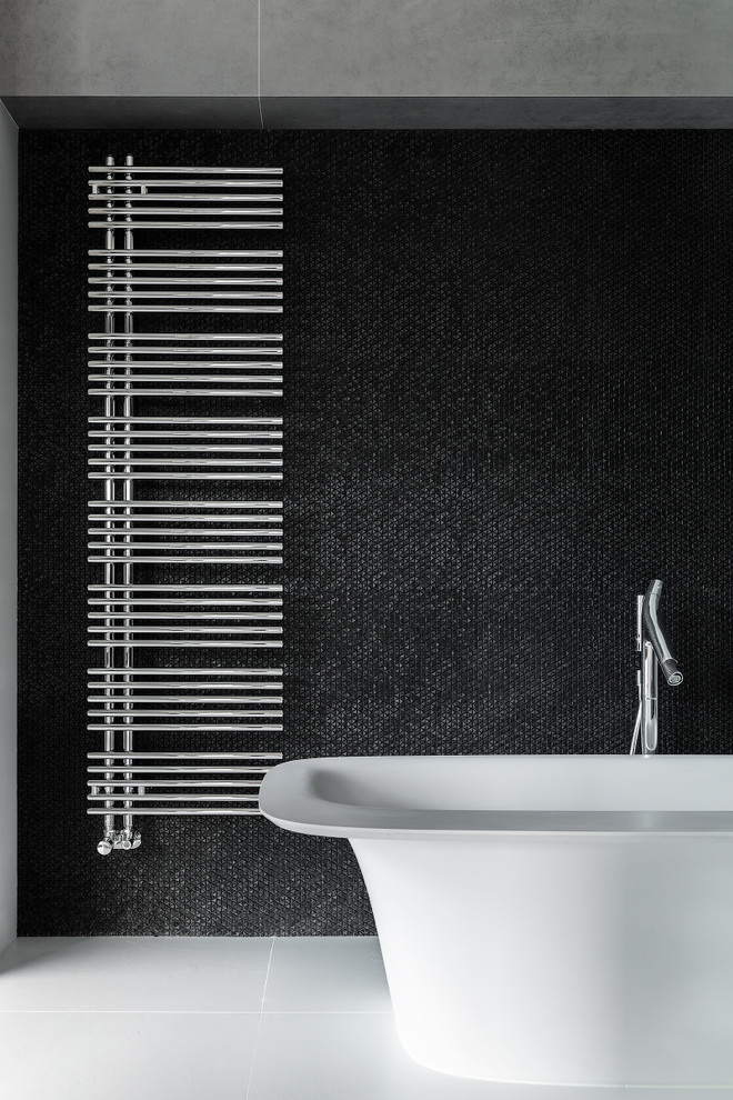 Идея дизайна: ванная комната с отдельно стоящей ванной, черной плиткой и белым полом