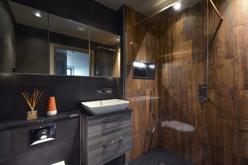 Photo of a contemporary shower room bathroom in London with flat-panel cabinets, grey cabinets, a corner shower, black tiles, brown tiles, black walls, a vessel sink, black floors, an open shower and black worktops.