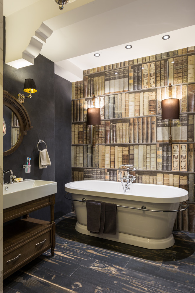 Cette photo montre une salle de bain principale éclectique en bois foncé avec une baignoire indépendante, un lavabo intégré et un sol noir.