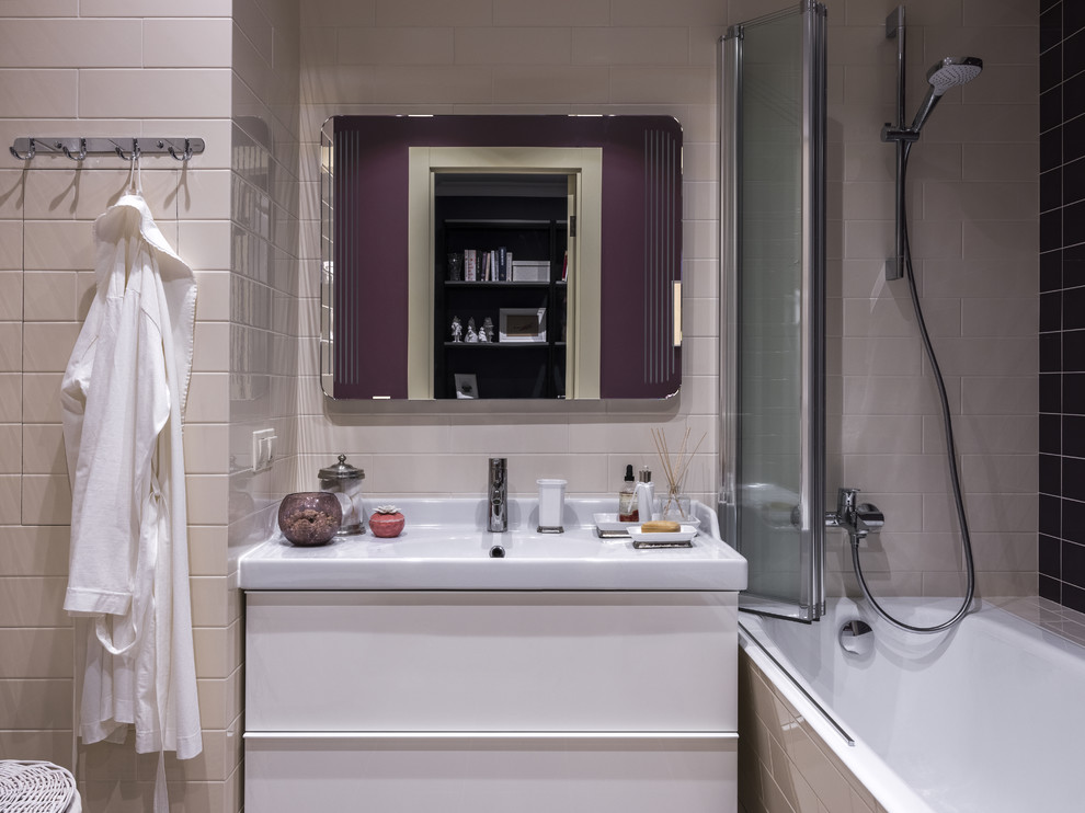 Inredning av ett klassiskt mellanstort vit vitt en-suite badrum, med släta luckor, vita skåp, en dusch/badkar-kombination, keramikplattor, ett badkar i en alkov, beige kakel, ett integrerad handfat, en vägghängd toalettstol, flerfärgade väggar, klinkergolv i keramik, vitt golv och dusch med duschdraperi