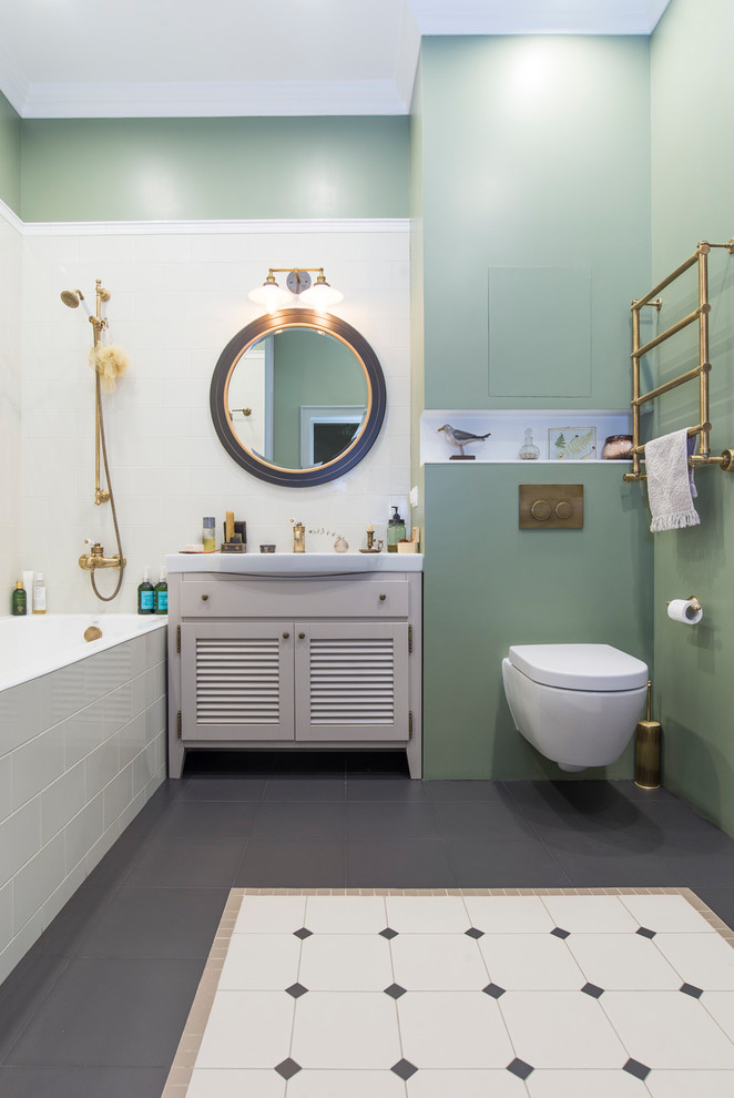 Foto på ett vintage en-suite badrum, med luckor med lamellpanel, grå skåp, ett badkar i en alkov, en dusch/badkar-kombination, en vägghängd toalettstol, vit kakel, gröna väggar och ett integrerad handfat
