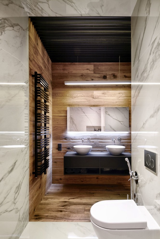 Exemple d'une petite salle de bain tendance avec WC suspendus, un carrelage blanc, des carreaux de porcelaine, une vasque, un placard sans porte, des portes de placard noires, un mur marron et un sol en bois brun.