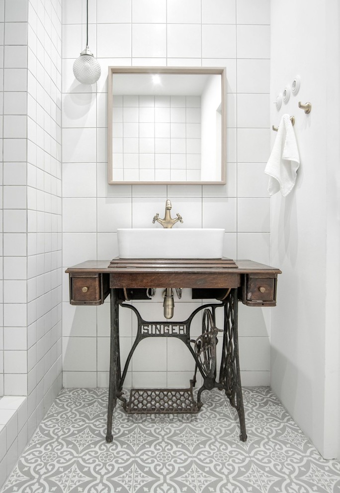 Bild på ett litet funkis brun brunt badrum, med vit kakel, keramikplattor, klinkergolv i keramik, ett fristående handfat, grått golv och träbänkskiva