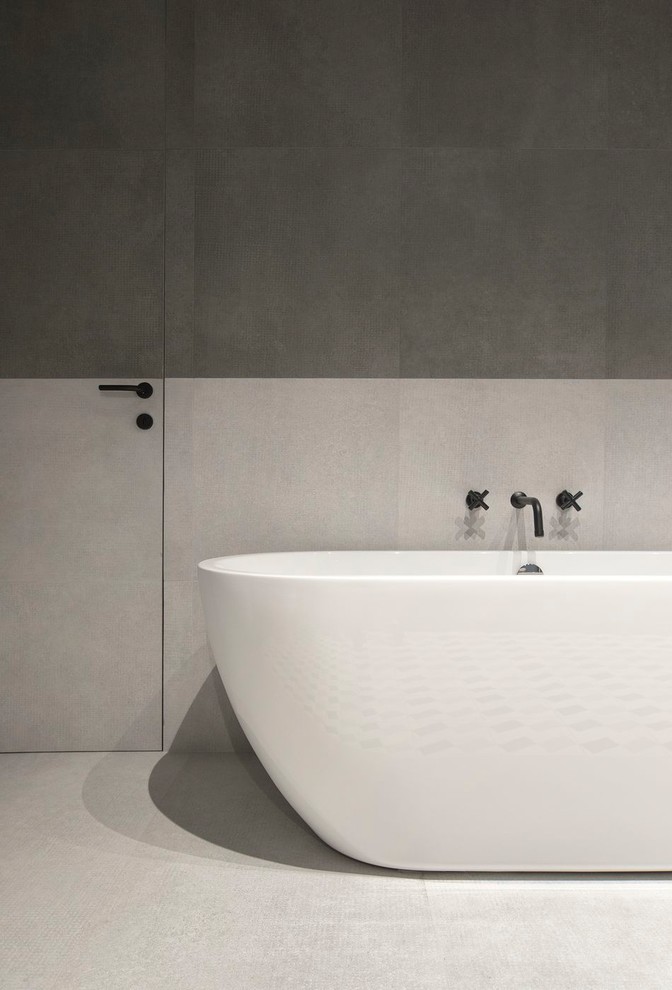 На фото: главная ванная комната в современном стиле с отдельно стоящей ванной, серой плиткой, керамогранитной плиткой, полом из керамогранита и серым полом с