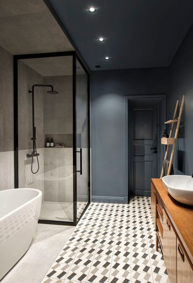 Пример оригинального дизайна: большая главная ванная комната в современном стиле с отдельно стоящей ванной, серой плиткой, керамогранитной плиткой, полом из цементной плитки, настольной раковиной, разноцветным полом, душем с распашными дверями, синими стенами, плоскими фасадами, фасадами цвета дерева среднего тона и угловым душем
