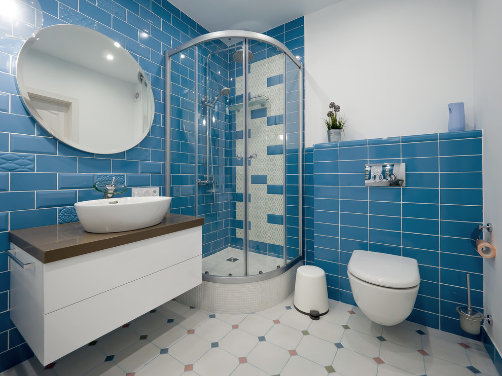Klassisk inredning av ett mellanstort badrum med dusch, med släta luckor, vita skåp, en jacuzzi, en hörndusch, en vägghängd toalettstol, blå kakel, keramikplattor, blå väggar, klinkergolv i keramik, ett fristående handfat, bänkskiva i akrylsten, vitt golv och dusch med skjutdörr