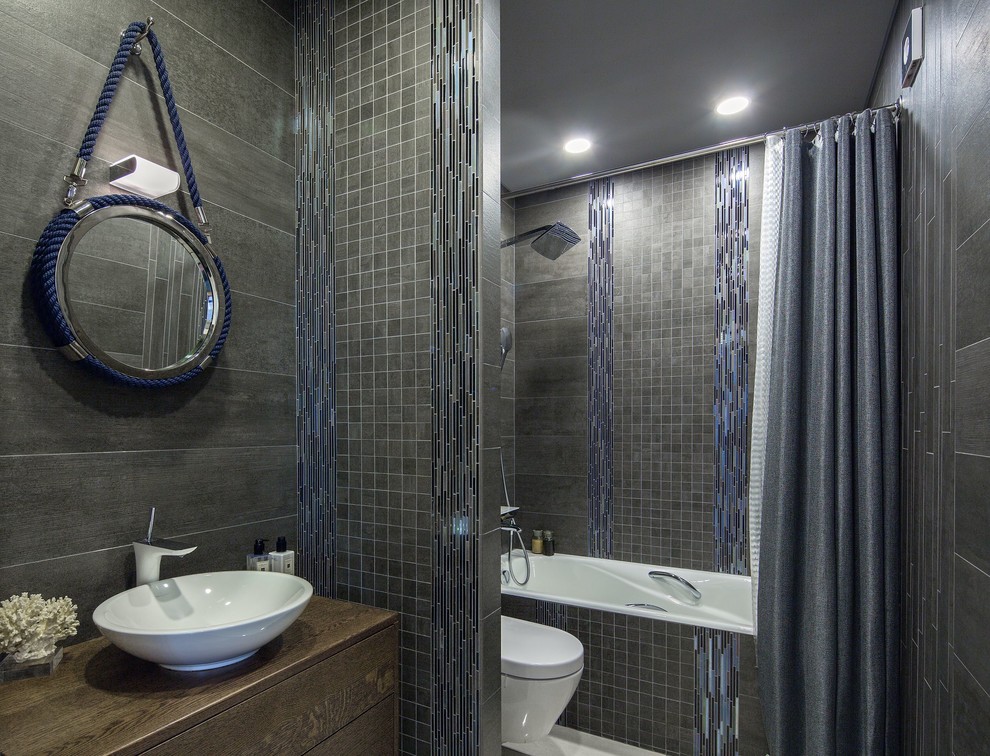 Идея дизайна: главная ванная комната в современном стиле с плоскими фасадами, темными деревянными фасадами, ванной в нише, душем над ванной, серой плиткой, настольной раковиной, столешницей из дерева, шторкой для ванной и коричневой столешницей