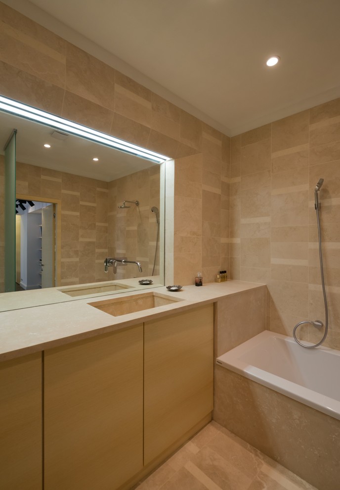 Medium sized contemporary ensuite wet room bathroom in Moscow with flat-panel cabinets, light wood cabinets, a submerged bath, a wall mounted toilet, beige tiles, stone tiles, beige walls, travertine flooring, a submerged sink and marble worktops.