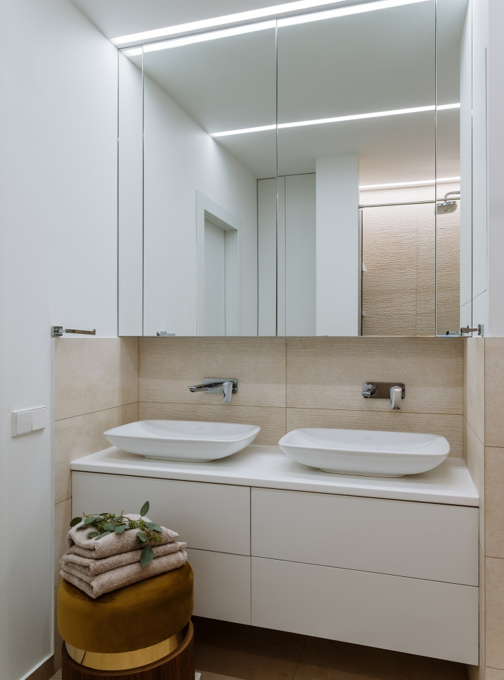 Modernes Badezimmer mit flächenbündigen Schrankfronten, weißen Schränken, beigen Fliesen, weißer Wandfarbe, Aufsatzwaschbecken, braunem Boden und weißer Waschtischplatte in Moskau