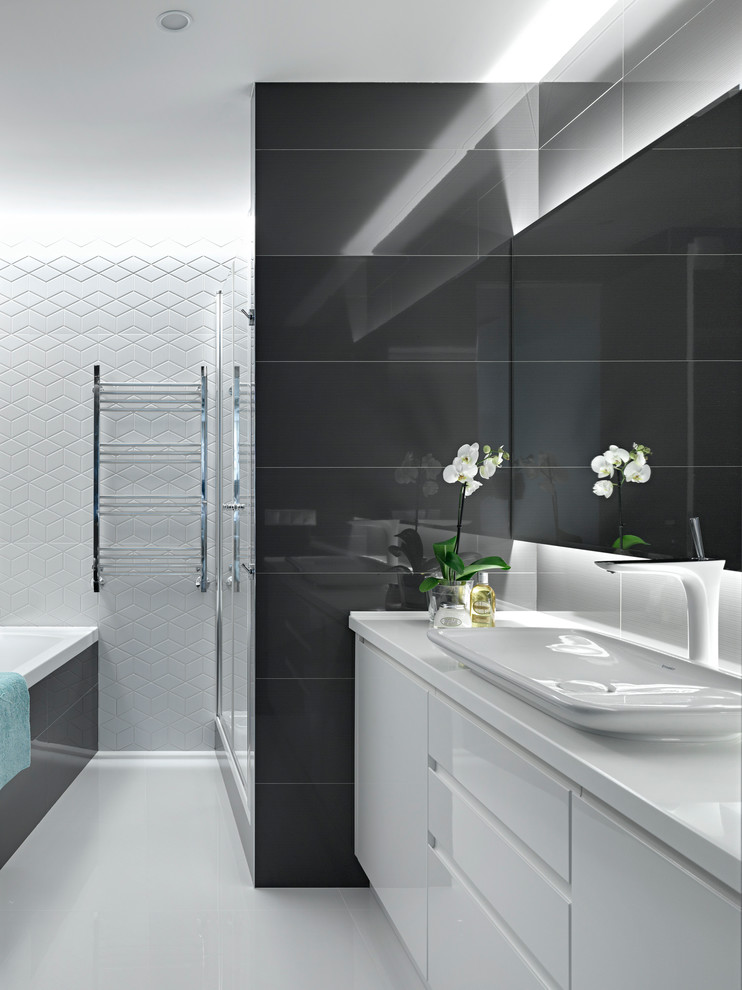 Пример оригинального дизайна: главная ванная комната в современном стиле с плоскими фасадами, белыми фасадами, настольной раковиной, черно-белой плиткой, керамогранитной плиткой, белыми стенами, полом из керамогранита, столешницей из искусственного камня и накладной ванной