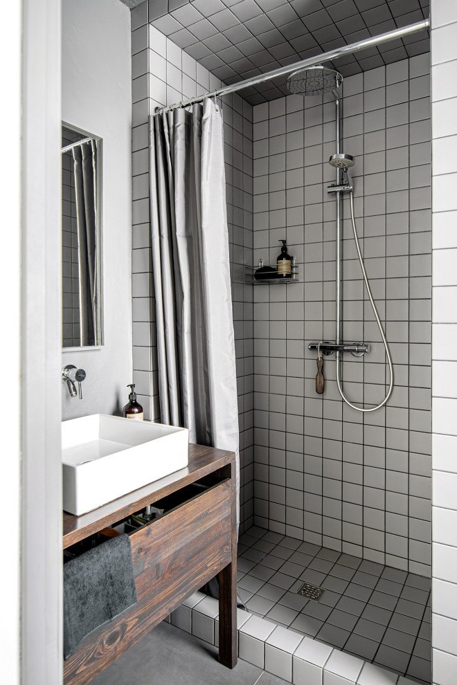 На фото: маленькая ванная комната в скандинавском стиле с душем в нише, серой плиткой, керамической плиткой, серыми стенами, полом из керамогранита, душевой кабиной, настольной раковиной, столешницей из дерева, серым полом, шторкой для ванной, коричневой столешницей, тумбой под одну раковину, напольной тумбой, плоскими фасадами и темными деревянными фасадами для на участке и в саду с