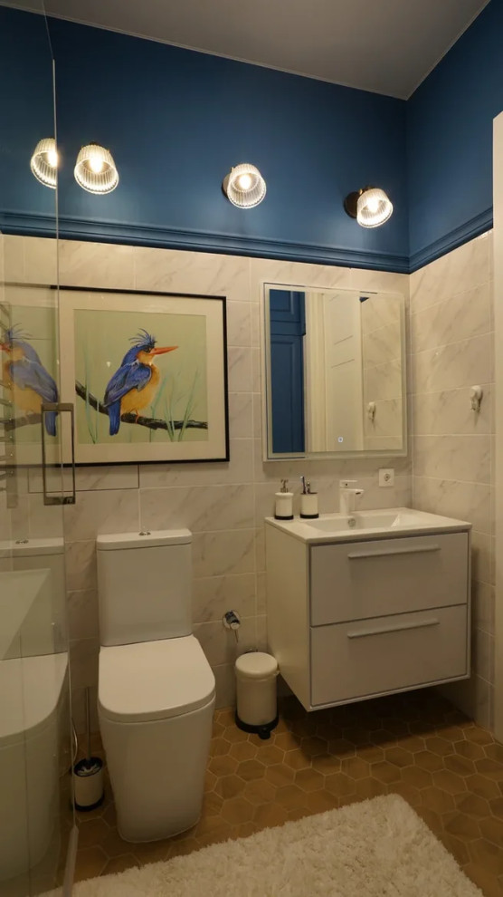 Modern inredning av ett mellanstort vit vitt en-suite badrum, med släta luckor, vita skåp, en dusch i en alkov, en toalettstol med hel cisternkåpa, vit kakel, keramikplattor, blå väggar, klinkergolv i keramik, ett väggmonterat handfat, marmorbänkskiva, beiget golv och dusch med gångjärnsdörr